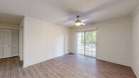 This well-appointed one-bedroom, one-bathroom residence in Herndon, Virginia offers a thoughtfully designed layout across a single floor. The open-concept living and kitchen area serves as the heart of the home, featuring light-toned hardwood-style flooring that flows seamlessly throughout. Crown molding and ceiling fans add refined detail to the living space, which is bathed in natural light and opens directly onto a private balcony through sliding glass doors — offering pleasant outdoor views of surrounding greenery.

The kitchen is a functional highlight, showcasing crisp white cabinetry, a granite-topped island with an undermount sink and brushed gold faucet, subway tile backsplash, and a full suite of stainless steel appliances including a gas range, built-in microwave, and refrigerator. A skylight above enhances the bright, clean atmosphere.

The bedroom is a comfortable, well-proportioned retreat with a ceiling fan, a window overlooking the lush exterior, and access to a dedicated closet. The bathroom is finished with granite counters, a soaking tub, and neutral tones throughout. Clean lines, light walls, and consistent flooring give the entire residence a cohesive, move-in-ready appeal.