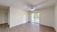 This well-appointed one-bedroom, one-bathroom residence in Herndon, Virginia offers a thoughtfully designed layout across a single floor. The open-concept living and kitchen area serves as the heart of the home, featuring light-toned hardwood-style flooring that flows seamlessly throughout. Crown molding and ceiling fans add refined detail to the living space, which is bathed in natural light and opens directly onto a private balcony through sliding glass doors — offering pleasant outdoor views of surrounding greenery.

The kitchen is a functional highlight, showcasing crisp white cabinetry, a granite-topped island with an undermount sink and brushed gold faucet, subway tile backsplash, and a full suite of stainless steel appliances including a gas range, built-in microwave, and refrigerator. A skylight above enhances the bright, clean atmosphere.

The bedroom is a comfortable, well-proportioned retreat with a ceiling fan, a window overlooking the lush exterior, and access to a dedicated closet. The bathroom is finished with granite counters, a soaking tub, and neutral tones throughout. Clean lines, light walls, and consistent flooring give the entire residence a cohesive, move-in-ready appeal.