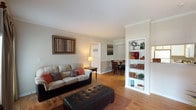 This single-floor, two-bedroom, two-bathroom residence offers a thoughtfully designed layout that balances comfort and functionality. The living area is anchored by warm hardwood flooring, crown molding, and a built-in display shelf, creating an inviting atmosphere. A sliding glass door allows natural light to fill the space, while a recessed entry nook adds architectural character. The living room flows naturally toward a dedicated dining area, which features two-tone walls with white wainscoting and hardwood floors throughout.

The kitchen is efficiently arranged with ample white cabinetry, a full suite of appliances including a refrigerator, electric range, and built-in microwave, plus granite-style countertops and hardwood flooring.

Both bedrooms are carpeted and include ceiling fans, sliding glass doors for natural light, and generous closet space. The primary bedroom features a walk-in closet. Each bathroom is equipped with a tub-shower combination, wood-look flooring, vanity with granite-style countertops, and practical linen storage. The overall aesthetic is warm and cohesive throughout.