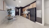 Located in Hartford, CT, this single-floor residence showcases a striking contemporary design that blends bold dark tones with warm natural wood accents throughout. The open-concept living and dining area features light-toned luxury vinyl flooring, recessed lighting, and a seamless flow that creates a spacious, airy feel. Large windows invite natural light into the space, enhancing the contrast between the dramatic charcoal-painted walls and the bright white ceiling and trim.

The kitchen is a standout feature, outfitted with flat-front wood-grain cabinetry, matte black hardware, a white subway tile backsplash, and white quartz countertops. A full suite of black appliances — including a refrigerator, electric range, microwave, and dishwasher — anchors the galley-style layout, which includes a matte black single-basin sink for a cohesive, modern finish.

The bedroom offers a calming retreat with clean white walls, light flooring, and a private entrance, providing a distinct separation from the main living area. The bathroom continues the design language of the unit, with deep charcoal walls, a wood-tone vanity with black fixtures, a glass-enclosed walk-in shower with white tile, and light flooring that ties the aesthetic together. Every detail of this well-appointed space reflects a refined urban design sensibility.