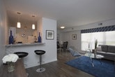 This single-floor residence at 1027 City Park Ave. in Portsmouth, Virginia offers a thoughtfully designed layout with multiple bedrooms, a functional kitchen, and a comfortable living area. The floor plan, as revealed in the 3D overview, flows naturally from room to room, creating a cohesive and practical living environment.

The kitchen is well-equipped with white cabinetry, granite-style countertops, white appliances including a range and refrigerator, and a stainless steel sink. Track lighting and light wood-style flooring give the kitchen a clean, contemporary feel. Ample cabinet storage and counter space make it a highly functional area.

The living room features a large sectional sofa, natural light streaming in through horizontal blinds, and carpeted flooring, creating a cozy and inviting atmosphere.

Both bedrooms are generously sized and feature the same durable wood-style plank flooring that runs throughout much of the home. The primary bedroom includes a walk-in closet and windows that allow natural light to fill the space. The second bedroom is equally well-appointed, with a dresser, mirror, and natural light from a side window. Neutral gray walls in the bedrooms provide a calm, versatile backdrop.

Overall, this residence combines modern finishes with practical design, offering a comfortable and stylish living experience in Portsmouth, VA.