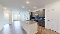 This thoughtfully designed single-floor residence offers three bedrooms, four bathrooms, and three closets across a generously proportioned floor plan. The open-concept kitchen and living area serves as the heart of the home, featuring warm wood-look flooring, recessed lighting, and a large center island topped with granite countertops and a deep undermount sink. The kitchen is further elevated by gray cabinetry, a striking navy blue subway tile backsplash, and a full suite of stainless steel appliances. A dedicated laundry area with a side-by-side washer and dryer is conveniently accessible from the main living space. The bright and airy living room boasts multiple windows that invite abundant natural light, a ceiling fan, and direct access to an outdoor balcony. The carpeted bedrooms offer a comfortable retreat, each with ceiling fans and ample closet space. The spacious primary suite includes a walk-in closet with built-in shelving and hanging rods. The bathrooms are finished with stylish tile work, including a standout walk-in shower adorned with white subway tile and decorative navy penny-tile accent bands with sleek glass enclosure. Throughout, the residence maintains a clean, contemporary aesthetic with white walls and modern hardware.