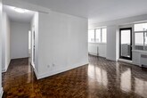 Located at 100 Gloucester Street in Toronto's Bloor-Yorkville neighbourhood, this one-bedroom, one-bathroom unit on the seventh floor offers a well-organized layout across a compact but efficiently designed floor plan. Polished parquet flooring flows consistently throughout the living areas and bedroom, lending warmth and a classic character to the space.

The living room is the largest area of the unit, featuring large windows and a glass balcony door that draw in natural light and provide views of the surrounding cityscape. A baseboard heating unit sits beneath the windows. The room connects directly to the bedroom, which also benefits from window exposure and includes a full-width mirrored sliding closet that enhances the sense of space.

The galley-style kitchen has been renovated with white shaker cabinetry, grey quartz countertops, a herringbone tile backsplash, stainless steel appliances including a full-size refrigerator, and light-toned tile flooring. The bathroom features a soaking tub with a chrome handheld shower fixture, fully surrounded by classic white subway tiles. A hallway connects the main entry to the rest of the unit, providing a practical transition between spaces.
