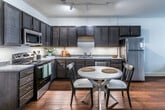 This single-story unit in Memphis, Tennessee offers a thoughtfully designed layout that makes efficient use of its space. The open-concept living and kitchen area serves as the heart of the unit, where warm hardwood-style flooring flows throughout, creating a cohesive and inviting atmosphere. The kitchen is well-equipped with dark espresso cabinetry, granite-style countertops, and a full suite of stainless steel appliances, including a refrigerator, dishwasher, microwave, and electric range. A small dining area adjacent to the kitchen provides a functional space for everyday meals.

The living area offers ample room for comfortable seating and benefits from natural light streaming through multiple windows fitted with horizontal blinds. Track lighting and ceiling-mounted fixtures provide additional illumination throughout the unit.

The bedroom is a calm, comfortable retreat featuring hardwood-style flooring, two windows that bring in natural light, and a ceiling fan for climate control. The full bathroom is clean and functional, featuring a tub-shower combination with tiled surround, granite-topped vanity, hardwood-style flooring, and built-in shelving for added storage convenience.