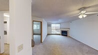 This single-floor residence offers a well-organized layout designed for comfortable everyday living. The spacious living room serves as the heart of the home, highlighted by a tile-surround fireplace and a ceiling fan with integrated lighting. Large windows fitted with vertical blinds allow natural light to fill the room, while baseboard heating runs throughout. A wall-mounted air conditioning unit provides additional climate control. Neutral carpet flooring extends across the living area and connects seamlessly to the adjacent rooms.

The kitchen is equipped with warm-toned wood cabinetry offering generous upper and lower storage, complemented by laminate countertops, a stainless steel sink, and black appliances including a range and over-the-range microwave.

The two bedrooms are carpeted and comfortably sized, each featuring windows with natural views and baseboard heating. One bedroom includes a wall-mounted air conditioning unit for independent temperature control.

The hallway provides practical storage through multiple closets with sliding and hinged oak-toned doors, leading to the bathroom, which features tile flooring, a shower-tub combination, and a vanity. The textured ceilings throughout contribute to a consistent, cohesive aesthetic across the entire space.