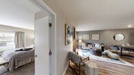 This thoughtfully designed single-floor residence offers a cohesive layout that balances comfort and functionality. The welcoming entryway opens into a bright hallway, adorned with gold-framed artwork, that leads seamlessly into the main living area. The living room is finished with warm wood-look flooring and neutral gray walls, creating an inviting atmosphere complemented by decorative wall art and a vibrant teal area rug that adds a pop of color to the space.

The kitchen is well-equipped with warm wood cabinetry, light stone countertops, and a peninsula that doubles as a breakfast bar. It flows directly into a dedicated dining area, keeping the space open and connected. A full bathroom features wood-look flooring and a shower-tub combination.

The primary bedroom is a serene retreat, highlighted by a bold blue accent wall, plush carpeting, and a large window that allows ample natural light to fill the room. A second bedroom offers similar comfort with soft carpeting, neutral walls, and access to a walk-in closet. Rounding out this residence is a dedicated laundry area housing a full-size side-by-side washer and dryer, adding a practical and convenient touch to everyday living.