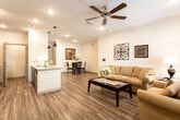 Located at 1607 N Midland Dr in Midland, TX, this single-story unit offers a thoughtfully designed open-concept layout that connects the living, dining, and kitchen areas into one cohesive space. Wood-look plank flooring runs throughout the main living areas, lending warmth and continuity to the design. The living room is generously proportioned, featuring a ceiling fan, recessed lighting, a smart thermostat panel, and a window that brings in natural light.

The kitchen is well-equipped with dark, medium-toned cabinetry, granite countertops, a tile backsplash, stainless steel appliances, and a peninsula that opens to the dining area — ideal for casual entertaining. A dedicated dining nook with ample wall space sits adjacent to the kitchen. Pendant lighting accents both the kitchen and dining areas.

The bedrooms feature plush carpeting, ceiling fans, and windows with exterior views. The bathroom includes a granite-topped vanity with dark cabinetry, a bathtub, wood-look flooring, and direct access to a walk-in closet. The overall aesthetic is clean and modern, with neutral white walls providing a versatile backdrop throughout the space.
