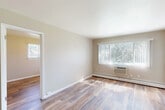 This single-floor, 3-bedroom, 1-bathroom unit offers a practical and well-organized layout designed to maximize every inch of available space. Consistent wood-look laminate flooring flows throughout all rooms, lending a clean, cohesive aesthetic that ties the entire unit together.

The spacious primary bedroom is a standout feature, bathed in natural light through large windows fitted with vertical blinds. A wall-mounted air conditioning unit provides individual climate control, while a baseboard heater ensures year-round comfort. The room also benefits from views of surrounding greenery. A dedicated closet with a built-in hanging rod provides convenient storage.

The additional bedrooms maintain a similar design, each featuring wood-look flooring, windows with natural light, baseboard heating, and neutral wall tones. One bedroom is further enhanced by a ceiling fan with integrated lighting.

The kitchen is equipped with stainless steel appliances, including a full-size refrigerator and electric range, complemented by warm-toned wood cabinetry overhead. The bathroom features a modern vanity with a white countertop, undermount sink, brushed nickel fixtures, and a large wall mirror.

Overall, this unit presents a clean, neutral palette with functional features throughout, making it a well-appointed and comfortable living space.