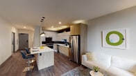 Located in the heart of Chicago's Loop at 29 S La Salle Street, Unit 311 is a well-appointed one-bedroom, one-bathroom apartment offering a thoughtfully designed open-concept layout. Dark hardwood floors run throughout the main living areas, anchoring the contemporary aesthetic and creating a cohesive flow between spaces.

The kitchen is a standout feature, showcasing a striking combination of white upper cabinetry and warm wood-toned lower cabinets, complemented by a bold dark chevron-patterned tile backsplash. Stainless steel appliances, including a gas range, dishwasher, microwave, and French door refrigerator, add a sleek, professional finish. A kitchen island with a white quartz countertop and pendant lighting serves as both a prep space and casual dining area with bar seating.

The living area is open and bright, with large windows allowing natural light and city views. The bedroom features plush carpeting, large windows with urban views, and direct access to a spacious walk-in closet with built-in shelving.

The bathroom is clean and modern, with large-format tile flooring, a floating wood-toned vanity with a rectangular mirror, and a tiled shower/tub combination. The overall design of the unit reflects a refined urban sensibility, balancing functionality with contemporary style throughout.