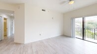 Located in Homestead, FL, this 2-bedroom, 2-bathroom residence offers a clean, modern aesthetic across a well-organized single-floor layout. Light wood-look flooring runs throughout, creating a cohesive and airy feel in every room. The kitchen is a functional galley-style space featuring white cabinetry with sleek hardware, granite countertops, a stainless steel sink, and white appliances including a refrigerator, range, and dishwasher. A peninsula with pendant lighting connects the kitchen to the living area, which benefits from a ceiling fan and sliding glass door access. The primary bedroom is a comfortable retreat with a walk-in closet and direct access to a private en-suite bathroom. The second bedroom offers mirrored sliding closet doors and black-framed windows that invite natural light and outdoor views. Both bathrooms are finished consistently, each featuring a tub-shower combination with tiled surround, chrome fixtures, and vanities with dark countertops and white cabinetry. Throughout the residence, elevated ceilings enhance the sense of space, and the neutral white walls provide a versatile backdrop. The layout also includes a dedicated closet for additional storage needs.