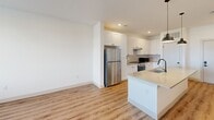 Located on E 65th Ave in Aurora, CO, this single-story residence offers a thoughtfully designed layout with one bedroom, one bathroom, and generous living space throughout. The open-concept kitchen serves as a focal point of the home, showcasing crisp white shaker cabinetry, subway tile backsplash, quartz countertops, stainless steel appliances, and a central island with a matte black faucet — all set atop warm-toned luxury vinyl plank flooring that extends through the main living areas. The bright, neutral palette and recessed lighting create a clean, modern ambiance throughout.

The bedroom is carpeted for comfort and features a window with blinds that brings in natural light. It connects to a well-appointed full bathroom with a white vanity, quartz countertop, matte black fixtures, a framed mirror with contemporary lighting, and durable LVP flooring. Accessibility features such as grab bars are also present. Adjacent to the bathroom is a spacious walk-in closet outfitted with multiple shelving tiers and hanging rods, providing ample storage. A hallway connects all areas of the home with ease, completing this well-organized and move-in-ready residence.