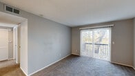 Located at 9534 NW 60th St in Parkville, Missouri, this single-story residence offers a practical and comfortable layout across several well-defined living spaces. Throughout the home, neutral gray walls and white trim create a clean, consistent aesthetic that complements the plush carpeting found in the living areas and bedrooms.

The living room is a notably spacious area highlighted by a sliding glass door fitted with vertical blinds, opening to a private balcony that overlooks mature trees, providing a natural outdoor view. The textured ceiling adds depth to the room while keeping the overall feel bright and open.

The kitchen features wood-look flooring, white cabinetry, and laminate countertops, providing ample storage and workspace. It is equipped with a range, black dishwasher, and a stainless steel refrigerator. A window above the sink allows natural light to fill the space.

The bedrooms are carpeted and well-proportioned, each featuring neutral tones and natural light from windows fitted with blinds. Ceiling fans with light fixtures are present in multiple bedrooms. At least one bedroom includes a double-door closet, offering practical storage.

The bathroom includes a full tub-shower combination with white tile surround and a window providing ventilation and additional natural light.