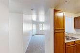Located at 801 Magnolia Ave in Corona, California, this single-floor residence offers a practical and well-organized layout with two bedrooms and two bathrooms. The kitchen is equipped with warm honey-toned wood cabinetry, granite-style countertops, a double-basin sink, and a white electric range, all set on light hardwood-style flooring. A pass-through window connects the kitchen to the living area, which features a ceiling fan and soft carpeting throughout. The living space flows naturally into a hallway that leads to the bedrooms and bathrooms. Both bedrooms are carpeted and filled with natural light from exterior-facing windows, offering a calm and comfortable atmosphere. The primary bedroom is a generous size and benefits from ample closet space, including a walk-in closet outfitted with multiple wire shelving units and hanging rods. Two additional closets provide further storage throughout the unit. The two bathrooms feature wood-toned vanities with granite-style countertops, large mirrors, and light hardwood-style flooring. White walls and clean finishes are consistent throughout the home, creating a bright, neutral interior that is easy to personalize.