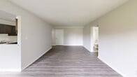 Located at 542 S Broadway in Pennsville, NJ, this one-bedroom, one-bathroom unit offers a well-organized single-floor layout designed for comfortable everyday living. The open living room is a bright, welcoming space highlighted by light wood-look luxury vinyl flooring, a textured ceiling, and dual sliding glass doors that flood the room with natural light and offer views of the surrounding greenery outdoors. The galley-style kitchen is a standout feature, showcasing rich dark gray cabinetry, light marble-look countertops, a stainless steel sink, and stainless steel appliances including a range and refrigerator — all complemented by the same wood-look flooring that carries through from the living area. A connecting hallway with built-in shelving leads to the rest of the unit. The generously sized bedroom features soft carpeting, a textured ceiling, a large window with vertical blinds for natural light, and multiple closet doors offering ample storage, with an in-unit laundry area also accessible from the bedroom. The bathroom is finished in a clean, all-white palette with tile-look flooring, a tub-shower combination, a white vanity, and modern fixtures. The overall aesthetic is clean, bright, and move-in ready.
