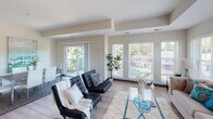 This single-floor residence in Robbinsdale, Minnesota offers a thoughtfully designed layout with modern finishes and a bright, welcoming atmosphere. The open-concept living area is a standout feature, bathed in natural light from a generous bank of large windows with plantation-style blinds. A sliding glass door leads to a private balcony, extending the living space outdoors with views of the surrounding neighborhood's mature trees.

The kitchen is well-equipped for both everyday cooking and entertaining, featuring rich dark cabinetry, granite countertops, a subway tile backsplash, stainless steel appliances including a gas range and French door refrigerator, and a central island topped with a striking industrial-style pendant light fixture. Light hardwood-style flooring runs throughout the main living areas, adding warmth and continuity.

The primary bedroom offers a serene retreat with a deep accent wall, plush carpeting, and a spacious closet. Its en-suite bathroom is finished with granite countertops, dark wood vanity cabinetry, tile flooring, and a glass-enclosed shower alongside a soaking tub. Additional bedrooms are generously sized with ample closet space and bright windows. A second full bathroom mirrors the quality finishes found throughout, with a tub-shower combination and hardwood-style flooring.