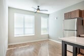 Located at 5567 Odana Rd in Madison, Wisconsin, this one-bedroom, one-bathroom unit offers a well-organized single-floor layout with a clean, contemporary design throughout. Light hardwood-style flooring flows seamlessly from room to room, creating a cohesive and bright aesthetic.

The kitchen is a standout feature, showcasing warm wood-tone cabinetry that extends to the ceiling, white quartz countertops, a geometric hexagonal tile backsplash, and a full suite of stainless steel appliances including a refrigerator, electric range, over-the-range microwave, and dishwasher. A freestanding island provides additional prep and dining space, while recessed lighting overhead ensures the area is well-lit.

The living and entry areas are open and airy, with large windows allowing natural light to fill the space. White panel doors and neutral gray walls throughout contribute to a modern, understated palette.

The bedroom is a comfortable size, featuring a bold dark teal accent wall, ceiling fan with integrated lighting, and a spacious closet with bifold doors and built-in shelving. The neutral tones of the remaining walls keep the room feeling fresh and versatile.

The bathroom is efficiently laid out with warm wood vanity cabinetry, a white countertop with an undermount sink, a large mirror, and light hardwood-style flooring that ties the space together. A separate area accommodates the shower, offering a practical and clean design.