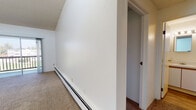Located at 2629 23rd Ave in Greeley, Colorado, this single-floor unit offers a functional and well-lit layout. The entry foyer features warm wood-look vinyl flooring and a baseboard heating unit, providing a welcoming transition into the main living spaces. The living area is a standout, boasting vaulted ceilings that create an impressive sense of height and openness. Natural light pours in through a sliding glass door that opens to a private balcony with outdoor views of the surrounding greenery. A wall-mounted air conditioning unit ensures year-round comfort. The carpeted bedrooms are bright and generously proportioned, each equipped with baseboard heating. One bedroom features high angled ceilings and a doorway leading to additional space, while another benefits from a large window with exterior views and a textured ceiling. The galley-style kitchen is efficiently designed with white cabinetry accented by warm wood trim, light countertops, wood-look vinyl flooring, and a window above the sink for natural light. Appliances include a refrigerator, electric range, and dishwasher. The bathroom is clean and straightforward, featuring a full tub-shower combination with white tile surround, a toilet, and a vanity with storage. Throughout, the unit maintains a clean, neutral palette.