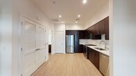 This single-floor residence showcases a clean, contemporary design with light hardwood flooring and recessed lighting carried consistently throughout the space. The kitchen is a standout feature, outfitted with rich dark espresso cabinetry that extends to the ceiling for ample storage, paired with crisp white quartz countertops and a classic white subway tile backsplash. A full suite of stainless steel appliances — including a gas range, built-in microwave, refrigerator, and dishwasher — equips the kitchen for both everyday cooking and entertaining. The kitchen flows openly into the main living area, which benefits from an airy, unobstructed layout. A louvered bifold door provides access to an additional space, adding functional versatility. The bedroom is a comfortable, well-proportioned room featuring light hardwood flooring, a ceiling fan, and a large sliding window that frames views of a greenery-filled outdoor area, allowing abundant natural light to fill the room. The bathroom is elegantly appointed with a full soaking tub and tub surround clad in crisp white tile, a dark vanity with a white quartz countertop, and a backlit frameless mirror that lends a modern, refined touch. The overall aesthetic is cohesive, blending modern finishes with a neutral palette for a fresh, move-in-ready environment.