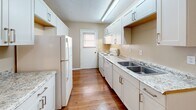 This single-story unit at 500 Rasco Rd W in Southaven, Mississippi, offers three bedrooms and one bathroom within a practical, efficiently arranged floor plan. Neutral beige walls and textured ceilings are consistent throughout, lending a cohesive, understated aesthetic across the space.

The living area is carpeted and features a ceiling fan with a light fixture, built-in floor vents for climate control, and a sliding glass door fitted with vertical blinds that allows natural light and outdoor access. An adjacent area with additional carpet and wall-mounted thermostat provides flexible use as a dining or secondary living space.

The galley-style kitchen is a functional highlight, featuring white cabinetry with brushed nickel hardware, granite-style countertops, a double-basin stainless steel sink, and warm hardwood-style flooring. White appliances including a refrigerator and electric range are included, with ample upper and lower cabinet storage.

The primary bedroom is notably spacious, featuring carpet, a ceiling fan, a window for natural light, and a double-door closet. The two additional bedrooms are carpeted and receive natural light through windows with blinds. The bathroom includes a tiled tub-shower combination, a vanity, and tile flooring.