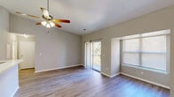 Located at 1700 N Dupont Hwy in Dover, Delaware, this one-bedroom, one-bathroom unit offers a well-organized single-floor layout designed for comfortable everyday living. The open-concept main area seamlessly integrates the living room, dining space, and kitchen, creating a bright and cohesive gathering space. The kitchen features white cabinetry, a range, a refrigerator, and a peninsula breakfast bar illuminated by pendant lighting, with a skylight above adding an extra touch of natural light. The living room is finished with hardwood-style flooring and includes a ceiling fan with light fixture. A sliding glass door opens to a private balcony, bringing in outdoor views and additional natural light. The generously sized bedroom provides a comfortable retreat, with a window allowing natural light and direct access to a hallway lined with multiple louvered-door closets, offering exceptional storage throughout. The unit includes a dedicated utility room and a full bathroom. Neutral-toned walls, clean white trim, and consistent hardwood-style flooring run throughout, contributing to a cohesive and modern aesthetic. Three closets provide abundant storage, making this a highly functional and well-appointed residence.