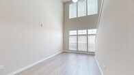 Located at 17880 E 64th Ave in Denver, CO, this two-bedroom, two-bathroom two-story home offers a thoughtfully designed layout spread across two floors. The main level features a bright living area with soaring double-height ceilings and large multi-pane windows that flood the space with natural light, complemented by light wood-style flooring. The kitchen is well-appointed with rich dark wood cabinetry, granite-look countertops, and a full suite of stainless steel appliances including a refrigerator, range, and over-the-range microwave. The upper level hosts a carpeted living or loft area with a ceiling fan and an open railing overlooking the lower floor. The bedrooms offer light wood-style flooring and ceiling fans, while the primary bedroom includes direct access to a full bathroom and a dedicated closet with built-in wire shelving systems for ample storage. A second closet provides additional organization. Both bathrooms are finished in neutral tones with clean, functional layouts. A carpeted staircase with a white handrail connects the two floors, adding warmth to the overall aesthetic. Neutral wall tones throughout create a clean, move-in-ready atmosphere.