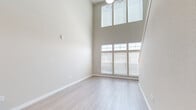 Located at 17880 E 64th Ave in Denver, CO, this two-bedroom, two-bathroom two-story home offers a thoughtfully designed layout spread across two floors. The main level features a bright living area with soaring double-height ceilings and large multi-pane windows that flood the space with natural light, complemented by light wood-style flooring. The kitchen is well-appointed with rich dark wood cabinetry, granite-look countertops, and a full suite of stainless steel appliances including a refrigerator, range, and over-the-range microwave. The upper level hosts a carpeted living or loft area with a ceiling fan and an open railing overlooking the lower floor. The bedrooms offer light wood-style flooring and ceiling fans, while the primary bedroom includes direct access to a full bathroom and a dedicated closet with built-in wire shelving systems for ample storage. A second closet provides additional organization. Both bathrooms are finished in neutral tones with clean, functional layouts. A carpeted staircase with a white handrail connects the two floors, adding warmth to the overall aesthetic. Neutral wall tones throughout create a clean, move-in-ready atmosphere.