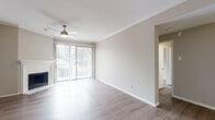 This single-floor residence offers a clean, modern aesthetic throughout, with wood-look flooring and a neutral color palette that creates a bright and cohesive atmosphere. The spacious living room serves as the heart of the home, highlighted by a classic corner fireplace, crown molding, a ceiling fan with light fixture, and sliding glass doors that open to a private balcony, filling the space with abundant natural light. Built-in shelving in an adjoining room provides practical display and storage space, complemented by recessed lighting and additional crown molding details. The galley-style kitchen is efficiently designed with white shaker cabinetry, dark countertops, subway tile backsplash, and a full suite of stainless steel appliances including a refrigerator, range, dishwasher, and microwave. The bedrooms are generously sized, each featuring ceiling fans, wood-look flooring, and windows with blinds that allow for natural light and privacy. The bathroom is well-appointed with a soaking tub and shower combination, a vanity with dark countertops, brushed nickel fixtures, and a large mirror. Throughout the residence, clean lines and consistent finishes contribute to a comfortable and functional living environment.