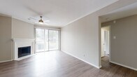 This single-floor residence offers a clean, modern aesthetic throughout, with wood-look flooring and a neutral color palette that creates a bright and cohesive atmosphere. The spacious living room serves as the heart of the home, highlighted by a classic corner fireplace, crown molding, a ceiling fan with light fixture, and sliding glass doors that open to a private balcony, filling the space with abundant natural light. Built-in shelving in an adjoining room provides practical display and storage space, complemented by recessed lighting and additional crown molding details. The galley-style kitchen is efficiently designed with white shaker cabinetry, dark countertops, subway tile backsplash, and a full suite of stainless steel appliances including a refrigerator, range, dishwasher, and microwave. The bedrooms are generously sized, each featuring ceiling fans, wood-look flooring, and windows with blinds that allow for natural light and privacy. The bathroom is well-appointed with a soaking tub and shower combination, a vanity with dark countertops, brushed nickel fixtures, and a large mirror. Throughout the residence, clean lines and consistent finishes contribute to a comfortable and functional living environment.