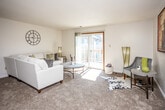 This single-floor residence offers a thoughtfully organized layout across several distinct functional areas. The living room serves as the central gathering space, featuring soft carpet flooring, a textured ceiling, and a sliding glass door that opens to a private balcony, allowing natural light to fill the room throughout the day. The balcony provides a pleasant outdoor extension ideal for relaxation.

Adjacent to the living area, the dining space features wood-look flooring and a ceiling fan with integrated lighting, offering a comfortable setting for meals. The galley-style kitchen is efficiently designed with warm wood cabinetry lining both sides, a double-basin sink, white appliances including a refrigerator, range, and microwave, and matching wood-look flooring that ties the space together.

The unit includes two carpeted bedrooms, each featuring multiple windows that bring in ample natural light and provide generous closet storage. The floor plan also includes two bathrooms, each equipped with a single vanity featuring wood cabinetry, a wide mirror, and wood-look tile flooring. Overall, the residence presents a functional and comfortable living environment with a cohesive, neutral aesthetic throughout.