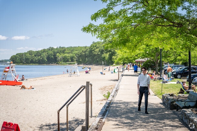 Visitors are basking in the sun and enjoying the beach at Goddard Memorial State Park Beach, RI.