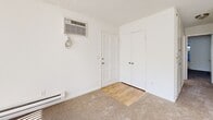 Located at 6166 Cottle Rd in San Jose, CA, this single-floor unit offers 3 bedrooms and 2 bathrooms with a practical, well-organized layout. The living area is bright and airy, featuring plush carpeting, a ceiling fan, and a large sliding glass door with vertical blinds that fills the space with natural light. The kitchen is outfitted with white cabinetry — both upper and lower — complemented by light stone-finish countertops and wood-look vinyl flooring, providing ample storage and workspace. The generously sized primary bedroom is the standout of the unit, offering abundant square footage, carpeted floors, and direct access to an en suite bathroom. The primary bath features wood-look flooring, a vanity with white cabinetry, a large mirror with overhead lighting, and a walk-in closet. The second bathroom is similarly appointed with a white vanity, stone countertop, and a shower-tub combo. The additional bedrooms are carpeted and well-lit, with windows overlooking greenery and closets for storage. A wall-mounted HVAC unit and baseboard heating are present throughout. Textured ceilings and clean white walls give the entire unit a bright, neutral aesthetic.