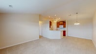 This single-story home offers a thoughtfully designed open-concept layout that seamlessly connects the living area to the kitchen. The spacious living room features soft carpeting, recessed lighting, and a ceiling fan with integrated lighting, creating a comfortable and airy atmosphere. A decorative chandelier accents the dining area nearby.

The kitchen is equipped with warm honey-toned cabinetry, a peninsula with a built-in sink and breakfast bar, white appliances including a refrigerator, electric range, and over-the-range microwave, and tile flooring that transitions cleanly from the carpeted living spaces.

The home includes two full bathrooms, each finished with light tile flooring, white vanity cabinetry, and chrome hardware. One bathroom features a shower-tub combination, while the second offers a standalone walk-in shower with a framed glass door. Bedroom closet storage is generous throughout, highlighted by a large walk-in closet with multi-tiered wire shelving and hanging rods, as well as a secondary bedroom with a double-door reach-in closet. Bedrooms are carpeted and include ceiling fans with windows allowing natural light. The attached two-car garage provides convenient interior access and is equipped with an automatic garage door opener.