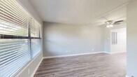 This single-story, 2-bedroom, 1-bathroom home offers a thoughtfully organized layout that maximizes every square foot. The living room serves as the heart of the space, featuring wood-look laminate flooring, soft gray walls, and a ceiling fan with light fixture. Large windows fitted with horizontal blinds allow generous natural light to fill the room, creating a bright and welcoming atmosphere. An entry door with a sidelight window connects seamlessly to the living area, which flows into a dedicated dining room. The kitchen is outfitted with light wood-look flooring, white cabinetry, stone-look countertops, and stainless steel appliances including a full-size refrigerator, complemented by a window that provides additional ventilation and light. Both bedrooms are carpeted and finished in neutral gray tones. The primary bedroom offers a comfortable footprint, while the second bedroom features dual windows on adjacent walls, flooding the space with natural light. One bedroom includes a mirrored sliding-door closet with built-in shelving. The full bathroom is clean and bright, with white cabinetry, a tub-shower combo, and a small window. Additional features include a hallway, utility room, and two closets for ample storage throughout.