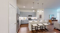 Located in Fort Worth, Texas, this thoughtfully designed two-bedroom, two-bathroom residence offers a comfortable and modern living experience across a single floor. The open-concept kitchen and living area serves as the heart of the home, featuring grey shaker-style cabinetry extending to the ceiling for ample storage, crisp white countertops, stainless steel appliances, and a peninsula with seating for casual dining — all illuminated by stylish pendant lighting. Wood-look flooring flows throughout the main living spaces, adding warmth and cohesion to the design. The living room is generously proportioned, bathed in natural light from multiple windows dressed with sheer curtains and blinds, and finished with a ceiling fan overhead. Both bedrooms offer comfortable dimensions, with the primary bedroom providing a well-sized retreat. Each bedroom is served by a dedicated closet featuring built-in shelving and hanging rods for organized storage. The two bathrooms mirror each other in finish quality, showcasing marble-style tiled tub and shower surrounds paired with wood-look flooring and grey cabinetry. Throughout the residence, a clean, neutral color palette creates a bright and inviting ambiance suited for modern living.