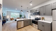 This thoughtfully designed 2-bedroom, 2-bathroom residence offers a functional and stylish single-floor layout with a seamless open-concept flow. The kitchen is a standout feature, showcasing gray shaker-style cabinetry, white quartz countertops, a subway tile backsplash, stainless steel appliances, and a peninsula with an integrated sink — all illuminated by pendant lighting and recessed fixtures. Light hardwood flooring runs throughout, unifying the space with warmth and continuity. The living area is bright and inviting, with large windows framing lush greenery views and providing generous natural light. The primary bedroom is a comfortable retreat, featuring dual windows with garden views and ample room for furnishings. Both bathrooms are finished with gray vanities, white quartz countertops, subway tile surrounds, and matte black fixtures — one with a walk-in shower and a backlit mirror, the other with a soaking tub and shower combination. Four closets, including walk-in storage options, offer exceptional organizational capacity. An in-unit stacked washer and dryer is conveniently tucked behind sliding doors. The overall ambiance is modern and clean, with a neutral palette that creates a calm and welcoming atmosphere throughout.