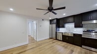 This efficiently designed 1-bedroom, 1-bathroom unit showcases a clean, modern aesthetic carried consistently throughout every room. Light-toned hardwood flooring runs seamlessly across the entire space, lending warmth and visual continuity. The open-concept kitchen and living area serves as the heart of the unit, featuring bold dark espresso shaker cabinetry that reaches toward the ceiling, contrasted by white granite countertops and a striking mosaic tile backsplash. A stainless steel farmhouse sink, dishwasher, refrigerator, and range complete the fully equipped kitchen. A ceiling fan with recessed lighting overhead adds both function and ambiance to the living area. The bedroom is a comfortable, well-proportioned room with its own ceiling fan, recessed lighting, and a window fitted with blinds that allows for natural light. A dedicated closet provides additional storage. The bathroom features a full tub-shower combination dressed in crisp white subway tile, accented by a built-in niche with a dark stone surround and granite shelf — a refined detail that elevates the overall design. Clean white walls and modern fixtures throughout contribute to the space's fresh, move-in-ready appeal.