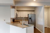 Located at 18248 W 12 Mile Rd in Southfield, Michigan, this single-floor, 2-bedroom, 2-bathroom residence offers a thoughtfully designed layout with a range of functional spaces including a den, dedicated laundry room, hallway, entrance, and a private patio. The open-concept kitchen and dining area is a standout feature, showcasing granite countertops, crisp white cabinetry with modern hardware, and stainless steel appliances including a French door refrigerator with ice maker, electric range with overhead microwave, and dishwasher. A peninsula with a dual-basin sink adds both style and practicality. The living room is bright and inviting, featuring dark hardwood-style flooring and sliding glass doors that open to the patio, flooding the space with natural light and outdoor views. The generously sized primary bedroom offers plush carpeting, a closet, and a window overlooking the grounds. The second bedroom mirrors this comfortable feel. Both bathrooms are finished with large-format tile; one features a walk-in glass-enclosed shower, while the other offers a full tub-shower combo, each with granite vanity tops and white cabinetry. Four closets throughout provide ample storage. The overall aesthetic is clean, modern, and move-in ready.