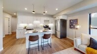 Located at 2115 Marshall Ave in Saint Paul's vibrant Merriam Park neighborhood, this single-floor unit offers a well-designed, modern living experience. The open living area greets you at the entry, featuring warm hardwood-style flooring, neutral toned walls, and large black-framed windows that bring in generous natural light and views of the surrounding streetscape. The kitchen is a standout, outfitted with crisp white shaker cabinets, granite countertops, stainless steel appliances, and under-cabinet lighting. A central island with bar seating and stylish pendant lights above makes this space as functional as it is attractive. The unit includes multiple bedrooms, each finished with the same hardwood-style flooring, neutral walls, and well-sized windows. Two full bathrooms serve the unit — one featuring a walk-in glass shower with granite-topped vanity, and the other a full tub/shower combo, also with granite counters and white cabinetry. Throughout, the finishes are consistent and contemporary, creating a cohesive, move-in-ready atmosphere. The thoughtful layout, quality materials, and abundance of natural light make this a comfortable and stylish place to call home.