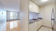 Located at 1170 Fisher Ave in Ottawa's desirable west end, this well-appointed 2-bedroom, 1-bathroom unit offers a functional and comfortable single-floor layout. Warm parquet flooring flows consistently throughout the living spaces, lending a classic character to the interior.

The open-concept kitchen is thoughtfully designed with white cabinetry, dark countertops, a double stainless steel sink, subway tile backsplash, and stainless steel appliances including a gas range, microwave, and refrigerator. A pass-through counter connects the kitchen to the spacious living room, which benefits from large windows that draw in natural light and offer views of the surrounding cityscape.

Both bedrooms feature the same distinctive parquet flooring, neutral walls, and built-in sliding closets, providing ample storage. The generously sized primary bedroom offers comfortable living quarters, while the second bedroom is well-proportioned for a variety of uses.

The bathroom is finished with clean white subway tile surrounding a full soaking tub and shower, accented by a taupe tile border and equipped with a grab bar for added accessibility. Baseboard heating is present throughout the unit, ensuring warmth during Ottawa's cooler seasons. The overall aesthetic is clean, bright, and move-in ready.