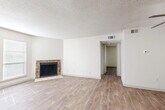 Located at 5616 Spring Valley Rd in Dallas, TX, this single-floor, two-bedroom, one-bathroom unit offers a practical and comfortable layout with consistent wood-style flooring running throughout the space. The living room serves as the centerpiece of the home, highlighted by a striking stone-surround fireplace and bright windows with blinds that allow natural light to fill the room. A textured ceiling and neutral white walls create a clean, understated backdrop throughout. The dining area transitions naturally into the galley-style kitchen, which features bold dark cabinetry, a mosaic tile backsplash, stainless steel appliances including a microwave and range, a double sink, and pendant lighting — making it both functional and visually distinct. The two bedrooms are well-proportioned, with the primary bedroom offering a closet and a window that brings in natural light. Both rooms share the same wood-style flooring and neutral tones found throughout the home. The full bathroom includes a tub-shower combination with white tile surround and wood-style flooring. Two closets provide practical storage, and a hallway connects the private areas of the home. The unit offers a cohesive, move-in ready interior in a convenient Dallas location.