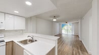 Located at 12375 SW 18th St in Miami, FL, this 2-bedroom, 2-bathroom residence offers a well-designed single-floor layout that maximizes comfort and functionality. The open-concept kitchen and living room serve as the heart of the home, where a peninsula with white quartz countertops seamlessly connects the two spaces. The kitchen is outfitted with white upper cabinetry, warm wood-toned lower cabinets, a tile backsplash, recessed lighting, and white appliances including a range, microwave, and refrigerator. Wood-look flooring flows throughout the entire residence, lending warmth and continuity to every room. The living area is generously sized, featuring a ceiling fan and large sliding glass doors that open to a balcony overlooking lush greenery, filling the space with natural light. The spacious primary bedroom includes a ceiling fan and ample closet storage. The second bedroom benefits from a large window with views of the surrounding tropical foliage. Both bathrooms are finished in a clean, modern style with large-format white tile flooring, wood-toned floating vanities, white quartz countertops, and glass-enclosed shower and tub combinations. A dedicated closet provides additional storage, completing this bright and move-in-ready Miami residence.