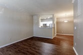 Located at 14604 Broadmoor St in Overland Park, Kansas, this single-story home features a cohesive design highlighted by rich wood-look flooring that runs throughout the entire residence. The open-concept living area is spacious and bright, with neutral-toned walls and clean white baseboards and crown molding that complement the warm flooring.

The kitchen is positioned at the heart of the home, defined by a peninsula with a pass-through opening that connects it to the living space. White cabinetry, light countertops, stainless steel appliances—including a refrigerator, microwave, and dishwasher—and track lighting overhead give the kitchen a functional, well-appointed character. A pendant light fixture marks the transition into the adjacent dining area.

The bedrooms continue the wood-look flooring theme and are equipped with ceiling fans. One bedroom features vaulted ceilings, multiple windows for natural light, built-in shelving, and a dedicated desk area. Another bedroom includes direct access to a walk-in closet and a connecting bathroom hallway.

The bathroom area includes a long vanity with white cabinetry, a light stone-look countertop, a large mirror, and a well-lit fixture above—providing ample preparation space. The overall ambiance of the home is clean, neutral, and move-in ready.