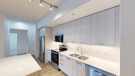 Located in Royal Palm Beach, FL, this single-floor, 3-bedroom, 2-bathroom residence offers a clean, modern design with thoughtful finishes throughout. The open kitchen is a standout feature, boasting floor-to-ceiling light grey cabinetry, gleaming white countertops, a classic subway tile backsplash, and a full suite of stainless steel appliances including a refrigerator with ice maker, electric range, built-in microwave, and dishwasher. Track lighting and warm wood-look flooring complete the kitchen's contemporary feel. The combined kitchen and living area provides a comfortable, open layout ideal for everyday living. Bedrooms feature plush carpeting, ceiling fans, and windows that invite natural light and views of lush greenery outside. The primary bedroom includes a dedicated walk-in closet with built-in shelving. Both bathrooms are finished in a crisp, neutral palette, each featuring a tub-shower combination with white tile surround and brushed nickel fixtures. A hallway connects the main living areas to the private bedroom wing, and a dedicated closet offers additional storage. The consistent use of light tones, wood-look flooring, and modern fixtures creates a cohesive, bright ambiance throughout the entire home.