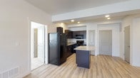 This single-floor residence features a well-designed open-concept layout where the kitchen and living areas flow seamlessly together. The kitchen is a standout space, outfitted with dark espresso cabinetry, granite-patterned countertops, and a full suite of black appliances including a refrigerator, range, microwave, and dishwasher. A central island with matching granite provides additional prep space and casual seating. Recessed lighting illuminates the kitchen, while light hardwood-style flooring extends throughout the main living areas, lending a clean, contemporary feel.

The living area is generously proportioned, featuring a flush-mount ceiling fixture and a glass-paneled exterior door that introduces natural light. The bedrooms are carpeted for comfort, each featuring windows with blinds that allow natural light while maintaining privacy. One bedroom includes a ceiling fan with a light kit and direct access to a bathroom. Two full bathrooms are present, each appointed with dark vanity cabinetry, granite-topped counters, tiled flooring, and a full soaking tub with shower. The overall aesthetic throughout is cohesive and modern, with neutral tones and consistent finishes connecting each space.