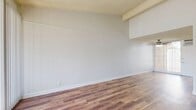 Located at 1125 Pine Ave in Redlands, CA, this single-floor, 2-bedroom, 2-bathroom home offers a well-organized layout designed for everyday comfort. The combined living and dining area serves as the heart of the home, featuring vaulted ceilings with an exposed beam, warm wood-look flooring, vertical blind-covered sliding glass doors that flood the space with natural light, and direct access to a private patio. A ceiling fan adds to the comfort of the space.

The kitchen is outfitted with white cabinetry, light stone-patterned countertops, a double-basin sink, and a full-size refrigerator, offering ample storage throughout. The generously sized primary bedroom includes two closets — one walk-in — providing excellent storage. The second bedroom features a large window with outdoor views and a ceiling fan. Both bedrooms carry the same wood-look flooring found throughout the home.

The two bathrooms are clean and functional, with one featuring a tub/shower combination with grab bars, a vanity with a light countertop, and matching wood-look flooring. A central hallway connects all rooms efficiently. Textured ceilings are consistent throughout, and the overall neutral color palette creates a bright, airy ambiance well-suited to the Southern California climate.