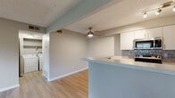 Located at 5304 S Broadway Cir in Englewood, CO, this single-floor, one-bedroom, one-bathroom unit offers a well-organized and functional layout. Light wood-style flooring runs throughout the space, creating a cohesive and clean aesthetic complemented by neutral gray and beige tones on the walls.

The open-concept living and dining area is anchored by a ceiling fan with a light fixture and connects seamlessly to the kitchen via a peninsula counter with a light-colored surface. The kitchen is well-appointed with white upper cabinetry, dark lower cabinetry, stainless steel appliances including a range, microwave, refrigerator, and dishwasher, and a stylish mosaic tile backsplash. Track lighting overhead keeps the space bright and functional.

The bedroom is a comfortable and well-proportioned retreat featuring large windows with blinds that bring in natural light and views of the surrounding greenery. A textured ceiling adds subtle dimension throughout the unit.

The bathroom includes a full tub-shower combination with white tile surround, a vanity with dark cabinetry and a light countertop, and wood-style flooring that ties into the rest of the home. A dedicated closet and hallway complete the layout, providing practical storage and flow between rooms.