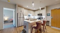 Located on Larchmere Boulevard in Cleveland's vibrant Larchmere neighborhood, this thoughtfully designed single-floor residence offers a seamless blend of modern finishes and functional living spaces. The open-concept kitchen is a standout feature, showcasing white shaker cabinetry with matte black hardware, a white quartz waterfall island with seating for two, stainless steel appliances, a subway tile backsplash, and elegant pendant lighting — all set atop warm hardwood flooring. The living and dining areas are bathed in natural light from large sliding glass doors and windows fitted with roller shades, creating a bright and airy atmosphere. The living room offers generous space for comfortable seating and entertainment. The bedrooms are carpeted for warmth and comfort, with large windows that frame neighborhood views and provide ample natural light. Two well-designed bathrooms feature white shaker vanities with stone countertops, matte black fixtures, large mirrors, and dark tile flooring. One bathroom includes a walk-in glass shower, while the other offers additional open shelving for storage. Throughout the residence, neutral tones, clean lines, and contemporary finishes create a cohesive and inviting ambiance.