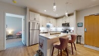 Located on Larchmere Boulevard in Cleveland's vibrant Larchmere neighborhood, this thoughtfully designed single-floor residence offers a seamless blend of modern finishes and functional living spaces. The open-concept kitchen is a standout feature, showcasing white shaker cabinetry with matte black hardware, a white quartz waterfall island with seating for two, stainless steel appliances, a subway tile backsplash, and elegant pendant lighting — all set atop warm hardwood flooring. The living and dining areas are bathed in natural light from large sliding glass doors and windows fitted with roller shades, creating a bright and airy atmosphere. The living room offers generous space for comfortable seating and entertainment. The bedrooms are carpeted for warmth and comfort, with large windows that frame neighborhood views and provide ample natural light. Two well-designed bathrooms feature white shaker vanities with stone countertops, matte black fixtures, large mirrors, and dark tile flooring. One bathroom includes a walk-in glass shower, while the other offers additional open shelving for storage. Throughout the residence, neutral tones, clean lines, and contemporary finishes create a cohesive and inviting ambiance.