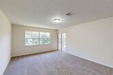Located at 4600 E Moody Blvd in Bunnell, Florida, this two-story, two-bedroom, two-bathroom residence offers a functional and comfortable layout across two floors. The main living level hosts the majority of the space, including a well-appointed kitchen featuring warm wood cabinetry, granite countertops, tile flooring, stainless steel appliances — including a range, microwave, and dishwasher — and a double-basin sink. The kitchen flows naturally toward a window overlooking lush greenery, creating a bright and pleasant atmosphere. Both bedrooms are carpeted and bathed in natural light, with windows framing views of surrounding trees. The primary bedroom includes access to a private balcony through sliding glass doors, offering a serene outdoor retreat. A closet with bifold doors provides convenient built-in storage. The two bathrooms are finished with tile flooring and surround tiling; one features a tub/shower combination with a decorative tile border accent, while the other offers a glass-enclosed shower. A dedicated laundry area adds everyday practicality. Textured ceilings, neutral wall tones, and consistent finishes throughout give the home a cohesive and move-in-ready feel.