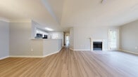 This single-story residence in Chattanooga, Tennessee offers a well-designed, open layout highlighted by notably vaulted ceilings that lend an expansive, airy quality to the living spaces. Light-toned hardwood-style flooring runs throughout the main living and kitchen areas, complementing the neutral, softly painted walls that create a clean and cohesive aesthetic.

The open-concept living room serves as the centerpiece of the home, featuring a classic fireplace with a white-painted mantle and dark tile surround. Vaulted ceilings in this space are enhanced by a ceiling fan with built-in lighting, while multiple windows allow natural light to fill the room. An exterior door provides convenient access directly from the living area.

The kitchen is configured with a raised breakfast bar peninsula, white cabinetry, stainless steel appliances including a microwave and refrigerator, and direct access to a walk-in pantry outfitted with built-in wire shelving—offering practical, organized storage.

Bedrooms feature plush carpeting, ceiling fans, and windows that invite natural light. Additional rooms with carpet flooring provide flexible use of space. The bathroom includes a full tub and shower combination with white tile surround and brushed nickel fixtures, maintaining the home's clean, neutral design throughout.